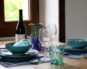 a table with plates and glasses and a bottle of wine at Chez Caro in Mourjou