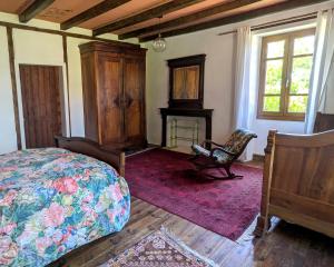 a bedroom with a bed and a chair and a fireplace at Chez Caro in Mourjou