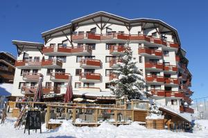 a hotel in the snow with a tree in front of it at Résidence Britania Clés Blanches in La Tania