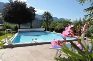 a swimming pool with two chairs and a table at Pension Margreth in Rifiano