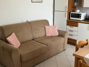 a brown couch in a kitchen with two pink pillows at Appartamento Ortensia in Fetovaia +1 photo