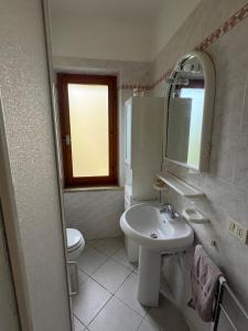 a bathroom with a sink and a toilet and a mirror at Appartamento Ortensia in Fetovaia