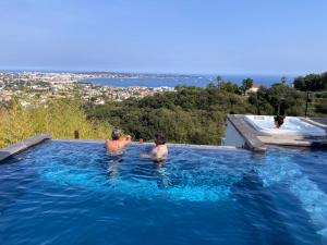 two people in a swimming pool in the water at Villa Bambou bei Cannes mit Blick auf Cap Antibes in Vallauris +26 photos
