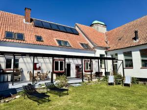 a house with a patio with chairs in the yard at Groland Bornholm B&B in Pedersker