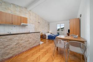 a kitchen with a table and chairs and a bedroom at Apartmani Petracie in Drvenik