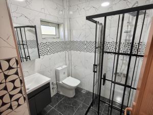a white bathroom with a toilet and a sink at Blue Park Beach Otel in Ayvacık