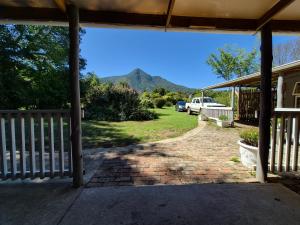a porch with a fence and a mountain in the background at Next to Heaven Guesthouse in Stormsrivier
