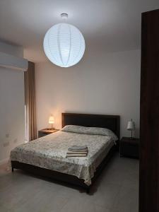 a bedroom with a bed and a large light at Link Point -Private room in shared Apartment in Misraħ Il-Barrieri