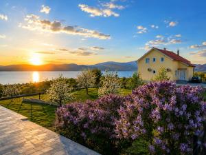 a house and flowers with the sunset in the background at Grabovica Sobe-Blue Lake Luxury Rooms in Grabovica