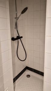 a shower with a hose in a white tiled bathroom at 17m2 Flower studio dans le centre historique Ecusson in Montpellier