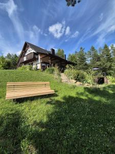 a bench sitting in the grass in front of a house at Woodland Apartment Small in Berezka