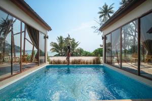 a woman standing in front of a swimming pool in a house at Moana Resort Koh Kood in Ban Lak Uan