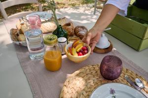 a table with a bowl of fruit and a person holding a bowl of orange juice at OlioeAlloro B&B in San Vincenzo