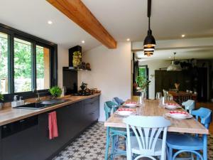 a kitchen with a wooden table and blue chairs at Maison paisible en lisière de foret 9 personnes in Le Temple