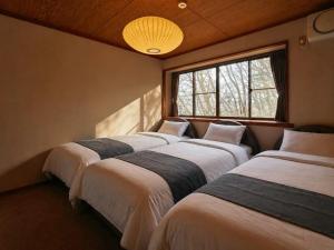 a row of four beds in a room with a window at NASU Fir Tree in Nasu