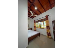 a bedroom with a bed and a window at minidu resort in Ambalantota