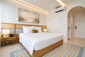 a bedroom with a large white bed and a door at Noska Hotel Sunset Town Sea View & Fireworks in Phú Quốc