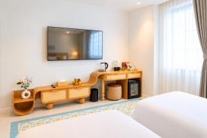 a room with a table and a tv on the wall at Noska Hotel Sunset Town Sea View & Fireworks in Phú Quốc