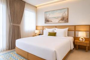 a bedroom with a large white bed and a window at Noska Hotel Sunset Town Sea View & Fireworks in Phú Quốc