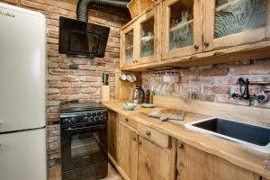 a kitchen with wooden cabinets and a brick wall at Podroom LauMarYvo in Dugo Selo