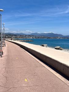 a empty sidewalk next to the water with a beach at De Gaulle 2 pièces Сentral Appartement in Cagnes-sur-Mer