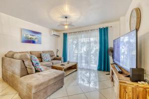 a living room with a couch and a flat screen tv at Villa Cardinal in Saint-Louis