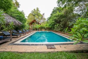 a swimming pool in the middle of a garden at Into The Wild Sigiriya in Sigiriya