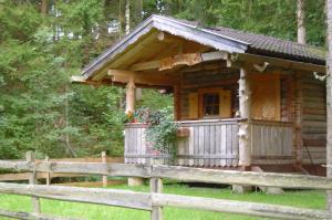 una cabaña de madera en el bosque junto a una valla en Haufhof-Pension am Bauernhof, Haus im Ennstal bei Schladming, en Haus im Ennstal