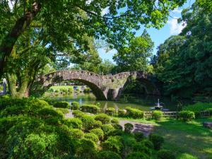 a stone bridge over a pond in a park at Isahaya Daiichi Hotel in Isahaya