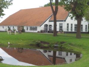 ein Haus mit einer Reflexion im Wasser in der Unterkunft bed en breakfast westerwolde in Sellingen