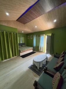 a living room with green walls and a couch and a table at Oliway Homestay in Lohaghāt