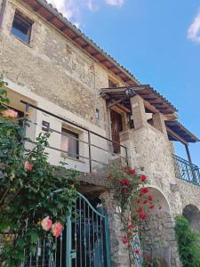 a stone building with a gate and roses at Casa di Ruggi in Tenaglie