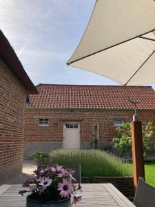 a table with an umbrella in front of a brick house at Maison Lion Luxe gastenverblijf in Borgloon