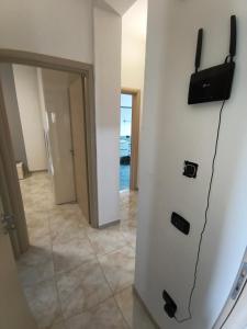a room with a television on a wall and a hallway at Dimora Melania in San Nicola Arcella