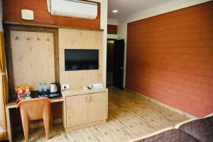 a room with a wooden wall with a desk and a television at HOTEL PARIJATHA Inn in Dharmastala