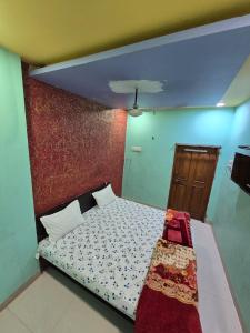 a bedroom with a bed and a wall at Shri Vinayak Guest House Omkareshwar in Godarpura