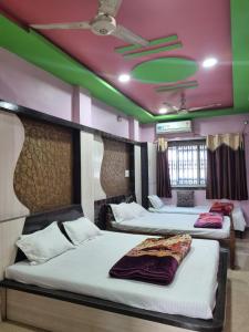 two beds in a room with a green and pink ceiling at Shri Vinayak Guest House Omkareshwar in Godarpura