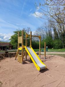 a playground with a yellow slide in the sand at Glamping La Jonquille in Hurecourt