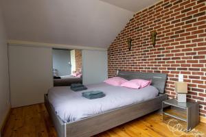 a bedroom with a brick wall and a bed with pink pillows at L'Escapade Albigeoise in Albi