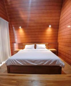 a bedroom with a bed with a wooden wall at Bale Rinjani Lodge & Cafe in Tetebatu +57 photos