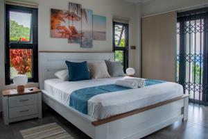 a bedroom with a white bed with blue sheets and windows at Fairview Heights in Victoria