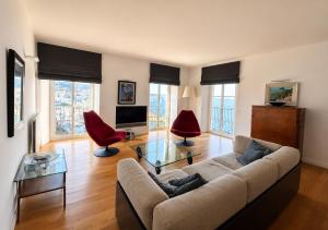 a living room with a couch and two red chairs at superbe appartement de prestige avec vue mer in Bastia