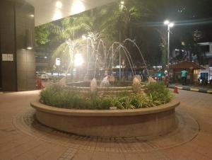 a fountain in the middle of a city at night at Elevate suite Hotel time square kl in Kuala Lumpur