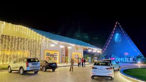 Eine Gruppe von Autos parkte vor einem Gebäude in der Unterkunft Hotel Bliss County in Dhule