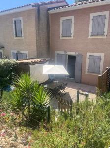 a patio with a white umbrella in front of a house at Maison avec jardin in Calvisson
