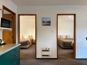 a room with two mirrors and a bedroom with a bed at ASURE Ambassador Motor Lodge in Oamaru