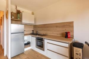 a kitchen with white cabinets and a white refrigerator at Chaleureux studio au pied des pistes - Le refuge in Les Déserts