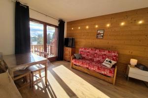 a living room with a red couch and a balcony at Chaleureux studio au pied des pistes - Le refuge in Les Déserts