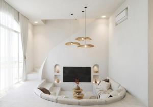 a white living room with a white couch and a tv at Svara Boutique Residences in Uluwatu