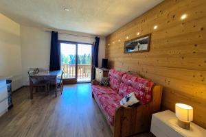 a living room with a red couch and a wooden wall at Chaleureux studio au pied des pistes - Le refuge in Les Déserts